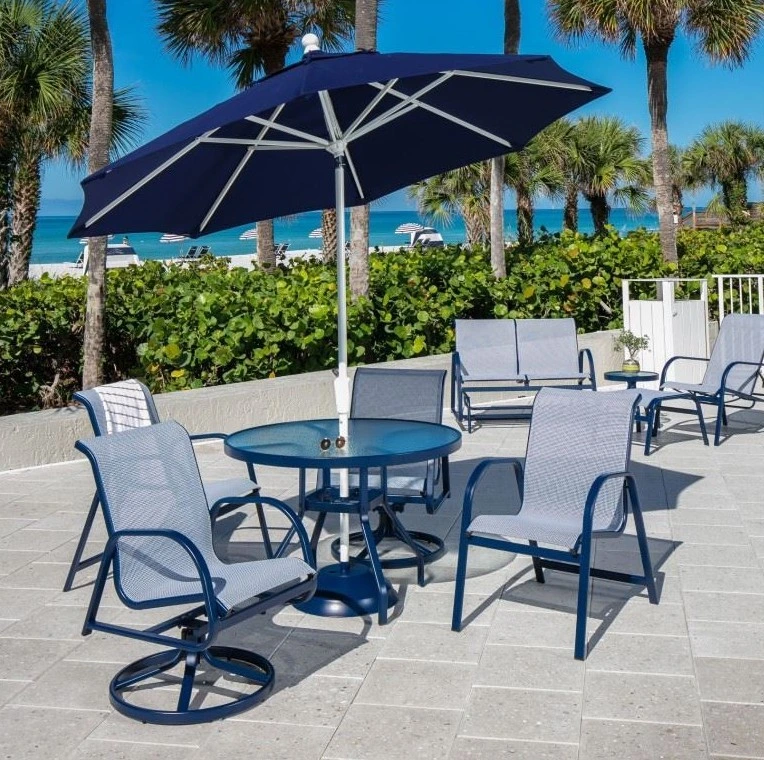 Ocean Breeze outdoor dining set with sling dining chairs and a navy market umbrella overlooking the beach and ocean.
